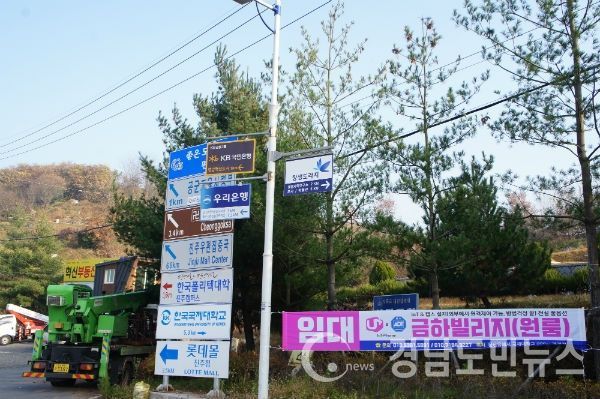 동진주 IC입구 교차로에 설치된 도로시설물인 가로등에 시중 대형은행 등 일부 업체들이 설치한 불법 광고물이 설치된 모습, 옆 시가 설치한 사설안내표지판에 대형 쇼핑몰이 불법으로 광고물을 설치한 모습/사진=조권래