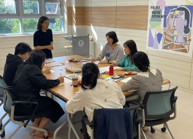 부모-자녀 미술치료 상호작용 놀이 준비를 위해 부모들이 사전 교육을 받고 있다