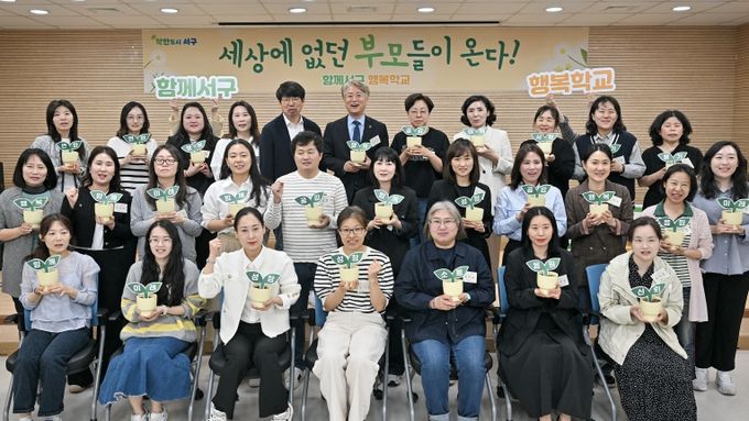 김이강 광주 서구청장이 24일 서구 화정청소년문화의집 멀티플레이실에서 열린 '함께서구 행복학교 1기 입학식'에서 행복, 성장, 미래 등 문구가 적힌 희망의 화분을 들고 참석자들과 기념촬영을 하고 있다.