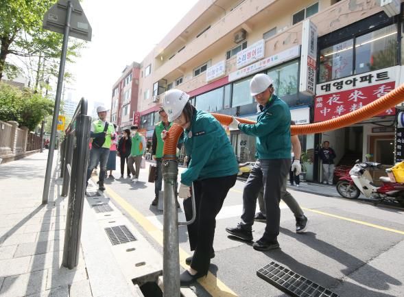 박희영 용산구청장이 빗물받이 정비 현장에 직접 참여하여 퇴적물과 이물질을 제거하는 작업을 하고 있다