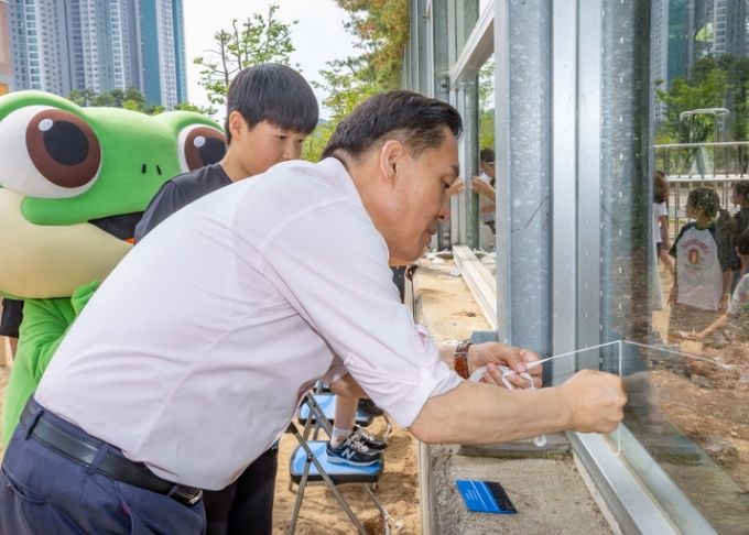 이재준 수원시장이 송림초등학교 학생들과 함께 야생조류 충돌방지 테이프를 붙이고 있다.