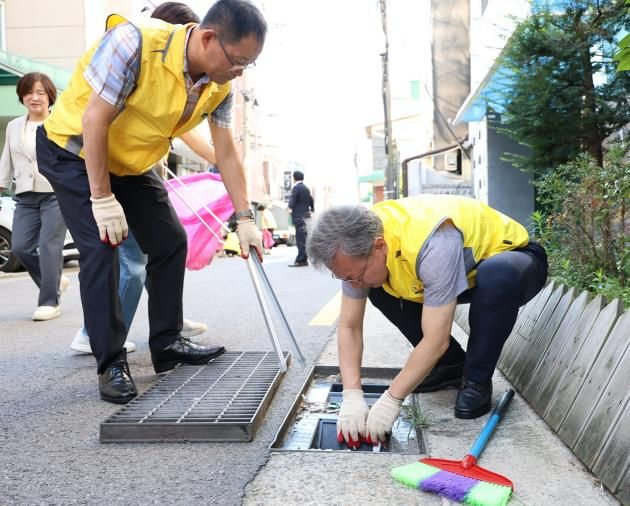 장인홍 구로구청장(오른쪽)이 7월 11일 주민들과 빗물받이를 청소하고 있다.