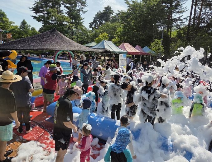 거품이 가득한 물놀이장에서 친구들과 함께 신나게 뛰노는 어린이들