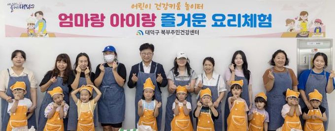 최충규 대덕구청장(사진 두 번째 줄 왼쪽 다섯 번째)과 ‘엄마랑 아이랑 즐거운 요리체험’에 참여한 가족들이 기념촬영을 하고 있다.