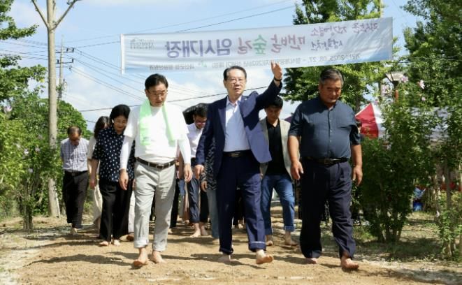 송인헌 군수와 참석자들이 성황천 맨발숲길 임시 개장식 후 맨발로 숲길을 걸으며 개장을 기념하고 있다