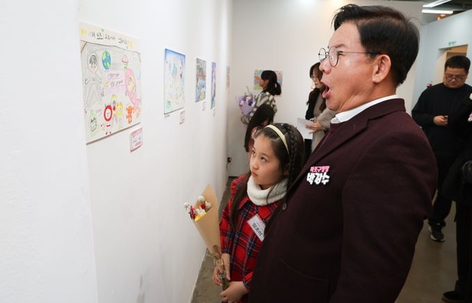 박강수 마포구청장이 수상 어린이와 함께 전시된 그림을 살펴보고 있다.