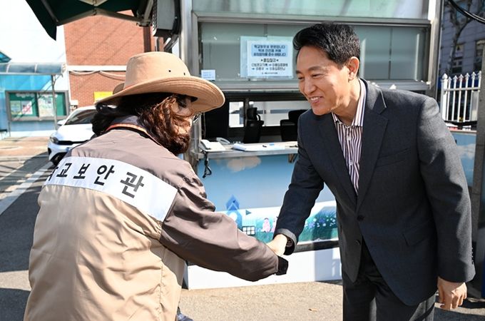 오세훈 서울시장이 13일 서울 소재 초등학교에서 학교보안관과 인사를 나누고 있다.